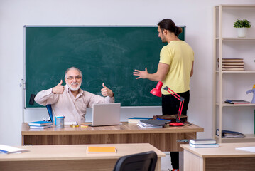 Old teacher and young male student in the classroom