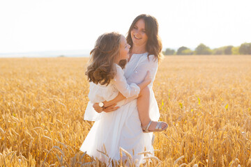 Happy mother and daughter time in a sunny field of wheat.