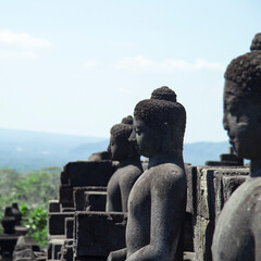 Fototapeta na wymiar Detail of the serene stone buddha sculptures or statues on top of the Borobudur Buddhist temple in Yogyakarta Indonesia Asia during a sunny day