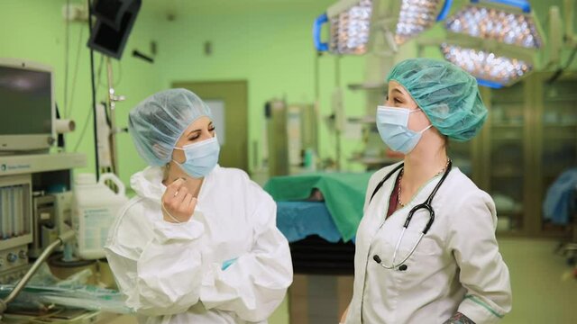 Female doctors stand and chat in medical face masks after surgery