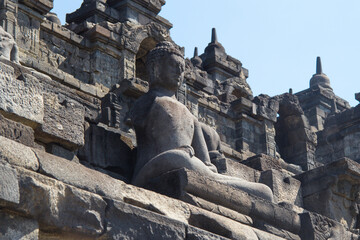 Obraz premium Stone sculpture detail of a seated buddha meditating on the walls of the Borobudur Buddhist temple in Yogyakarta Indonesia Asia
