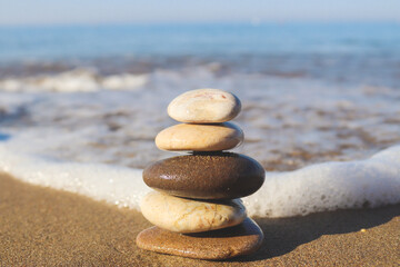 Fototapeta na wymiar Stack of stones on sea background, copy space, selective focus. The concept of sea vacation, stability, harmony and life balance. Zen concept