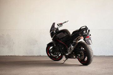 Sports black motorcycle on a background of an underground gray wall in the studio.