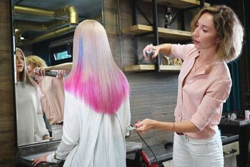 Beautiful blond girl with colored pink hair in a hairdressing salon.