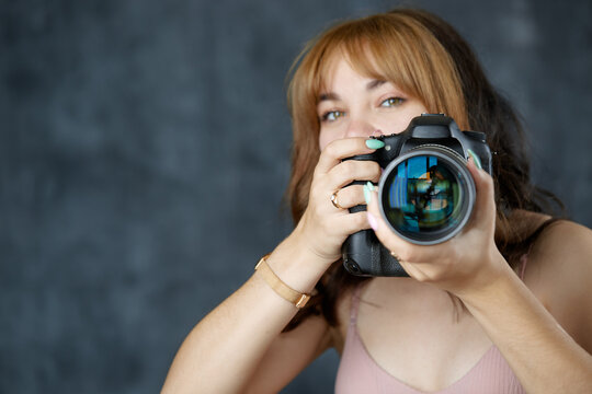 Portrait of a photographer covering her face with the camera. Young girl with a professional camera in her hands. Selective focus. Сoncept - stock image
