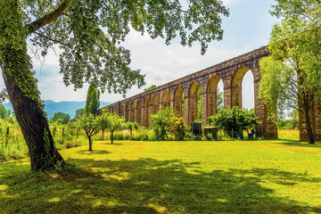 A view from a meadow of the impressive Nottolini aqueduct in Lucca Italy in summer