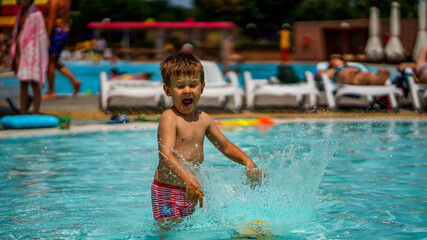 Naklejka premium Little cute boy playing in water in a water park