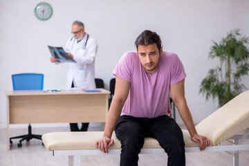 Old doctor radiologist examining young male patient