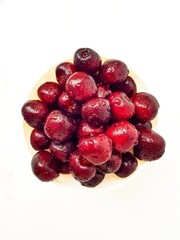 Bright juicy red cherry on a white background in drops of water.
