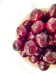 Bright juicy red cherry on a white background in drops of water.