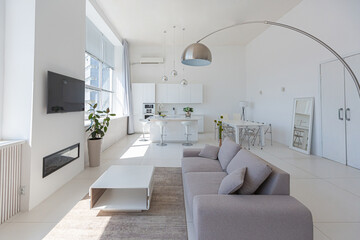 Cozy luxury modern interior design of a studio apartment in extra white colors with fashionable expensive furniture in a minimalist style. white tiled floor, kitchen, relaxation area and workplace