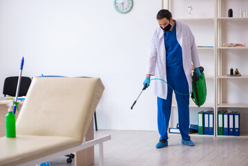 Young male contractor disinfecting clinic in pandemic concept