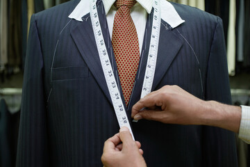 Tailor measuring business man for suit