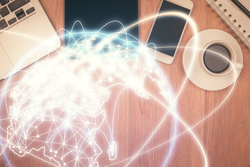 Double exposure of business theme hologram over desktop with phone. Top view. Mobile international...