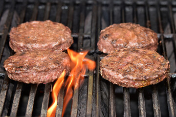 Flame-grilled hamburger patties on the grill.
