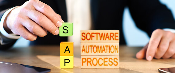 SAP concept. a man collects wooden blocks into the inscription Business process automation software and management software - obrazy, fototapety, plakaty