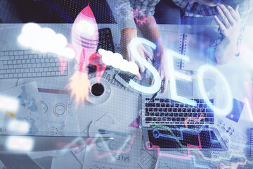 Double exposure of man and woman working together and SEO hologram drawing. Search engine concept. Computer background. Top View.