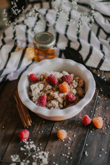 A delicious and healthy breakfast with raspberries and honey. Oatmeal for breakfast. Morning aesthetics and beautiful layout on a wooden table.