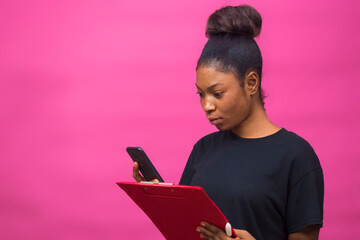 young beautiful black lady holding her notepad and using her smartphone check out something