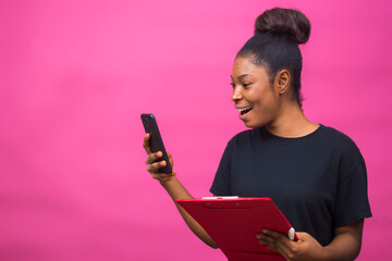 young beautiful black lady holding her notepad and happy over something she saw on her smartphone