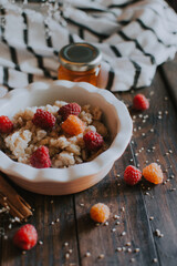 A delicious and healthy breakfast with raspberries and honey. Oatmeal for breakfast. Morning aesthetics and beautiful layout on a wooden table.