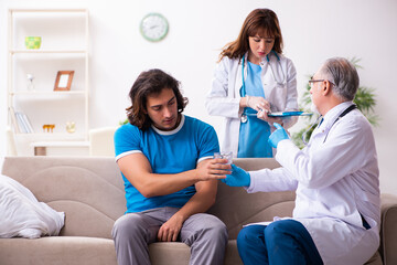 Two doctors visiting sick young man at home