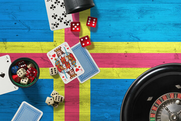 Aland Islands casino theme. Aces in poker game, cards and chips on red table with national wooden flag background. Gambling and betting.