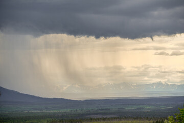 Moody and dark rain shower with storm clouds over a mountain scene. Taken in the summer in Yukon Territory, northern Canada.