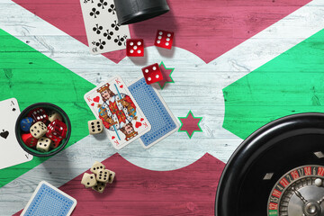 Burundi casino theme. Aces in poker game, cards and chips on red table with national wooden flag background. Gambling and betting.