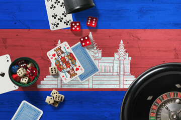 Cambodia casino theme. Aces in poker game, cards and chips on red table with national wooden flag background. Gambling and betting.