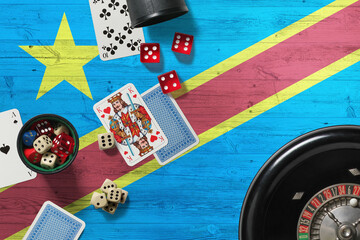 Congo casino theme. Aces in poker game, cards and chips on red table with national wooden flag background. Gambling and betting.