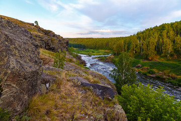 Ural Mountains. Rocks and rocky rifts on mountain river in summer. View on valley and the river Iset with rocky banks.
