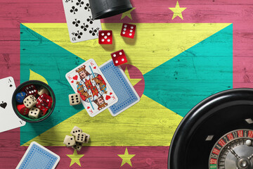 Grenada casino theme. Aces in poker game, cards and chips on red table with national wooden flag background. Gambling and betting.