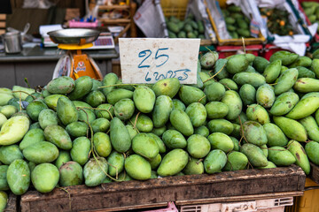 green mangoes lying on a market counter. Exotic fruits of Asia