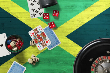 Jamaica casino theme. Aces in poker game, cards and chips on red table with national wooden flag background. Gambling and betting.