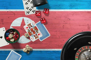 North Korea casino theme. Aces in poker game, cards and chips on red table with national wooden flag background. Gambling and betting.