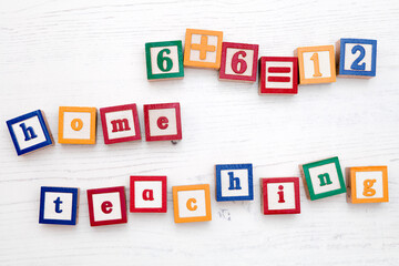 A set of children’s colourful wooden spelling blocks spell out the words ‘home teaching’.