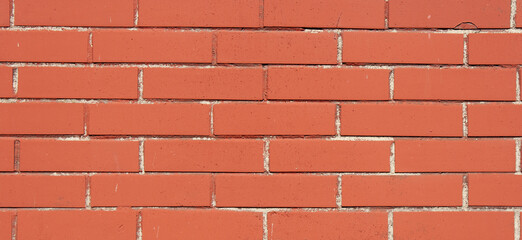 Obraz premium Red brick texture. Brown brick wall with uneven seam. Building pattern. The construction of a stone wall. Old concrete fence with a shadow from the sun. Close-up design. Banner for web site