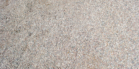 Gravel texture. Small stones, little rocks, pebbles in many shades of grey, white, brown, pink colour. Crushed granite texture. Road made of stones. Small rock background. Banner for web site.
