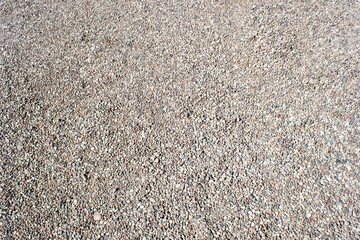 Gravel texture. Small stones, little rocks, pebbles in many shades of grey, white, brown, pink colour. Crushed granite texture. Road made of stones from river or lake. Small rock background