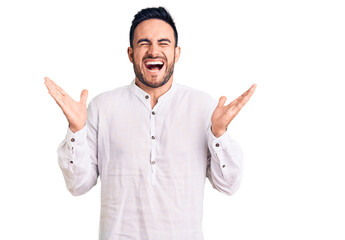 Young handsome man wearing casual clothes celebrating mad and crazy for success with arms raised...