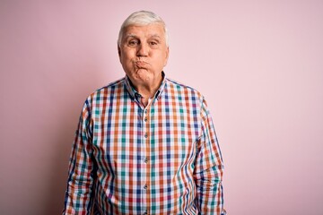 Senior handsome hoary man wearing casual colorful shirt over isolated pink background puffing cheeks with funny face. Mouth inflated with air, crazy expression.