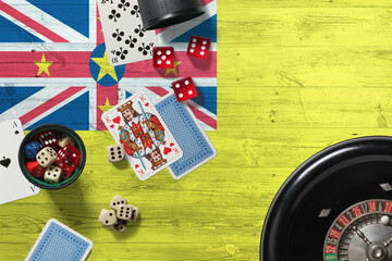 Niue casino theme. Aces in poker game, cards and chips on red table with national wooden flag background. Gambling and betting.
