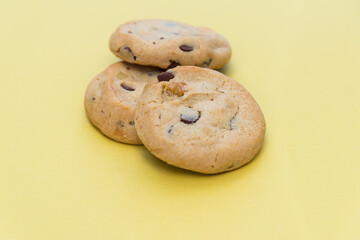 Stack of three chocolate chip cookies junk food isolated on yellow background