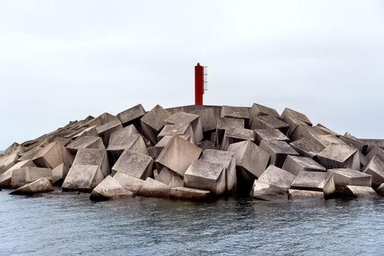 Breakwater with a small red lighthouse on top. Concept of resistance