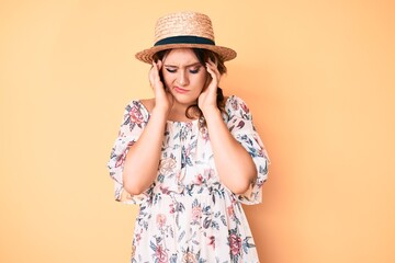 Young beautiful caucasian woman wearing summer dress and hat suffering from headache desperate and stressed because pain and migraine. hands on head.