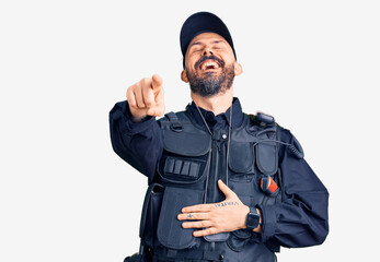 Young handsome man wearing police uniform laughing at you, pointing finger to the camera with hand over body, shame expression