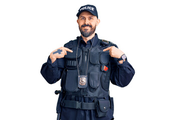 Young handsome man wearing police uniform looking confident with smile on face, pointing oneself with fingers proud and happy.