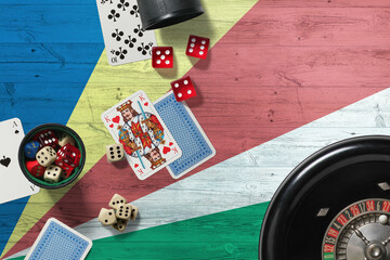 Seychelles casino theme. Aces in poker game, cards and chips on red table with national wooden flag background. Gambling and betting.