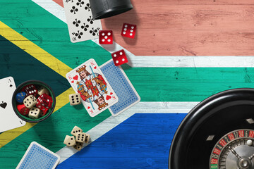 South Africa casino theme. Aces in poker game, cards and chips on red table with national wooden flag background. Gambling and betting.